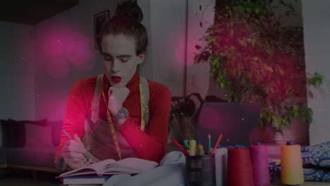 woman sketching business plan in studio, showcasing animated pink flares around laptop and notebook
