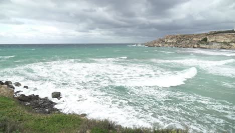 big mediterranean sea waves crashing on shore of one of malta's popular beaches