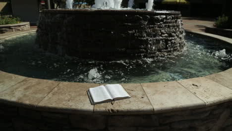 holy book by a peaceful water fountain background in slow motion