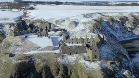 aerial view of dunnottar castle ruins surrounded by snow on a sunny winter day, nr stonehaven, aberdeenshire, scotland