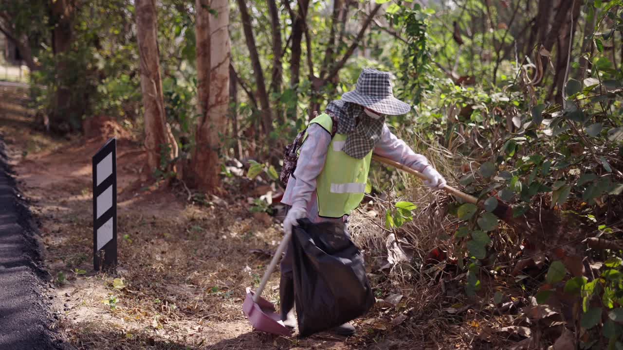 Persona che pulisce rifiuti e detriti lungo il bordo di una strada forestale