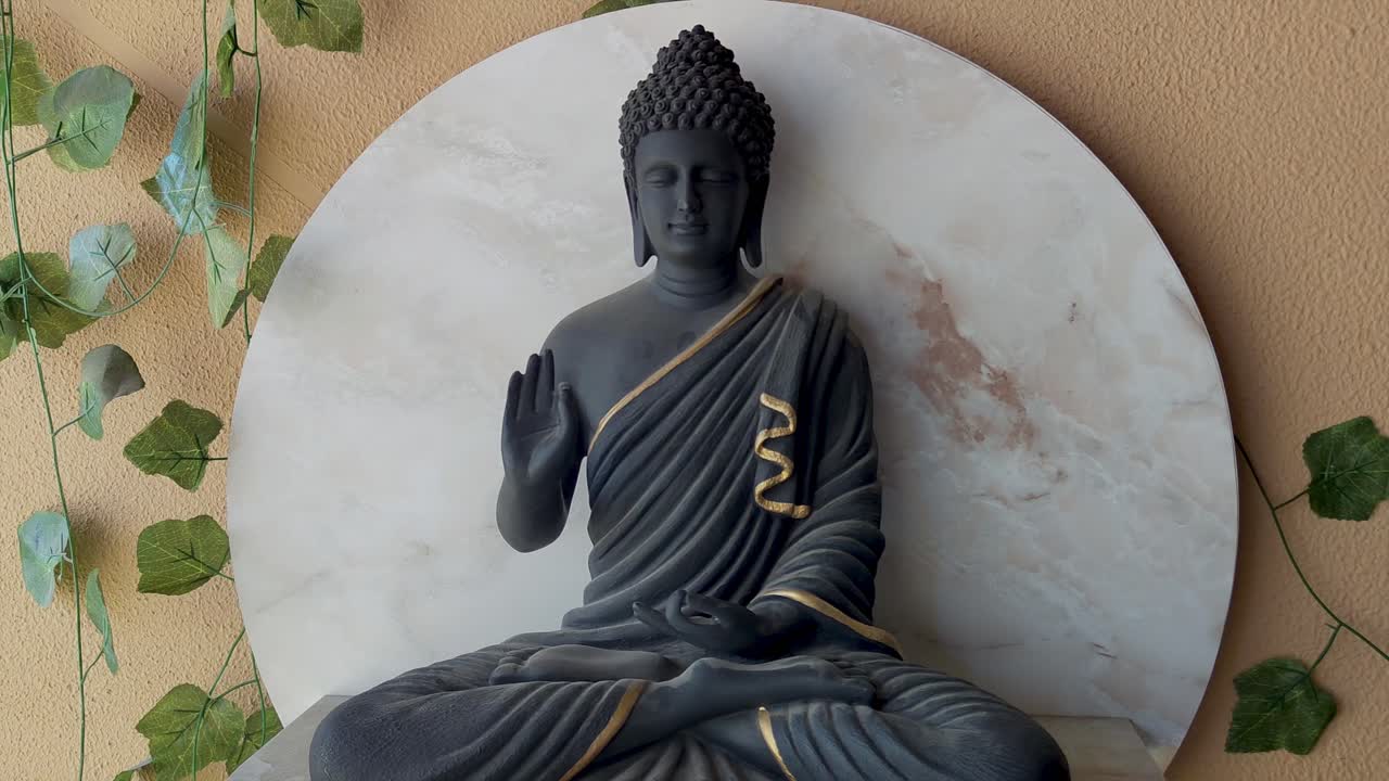 Aesthetic 4K footage of serene Buddha statue with gold accents, set against minimalist marble backdrop and greenery. meditation, mindfulness, spiritual ambiance and relaxation home decor.