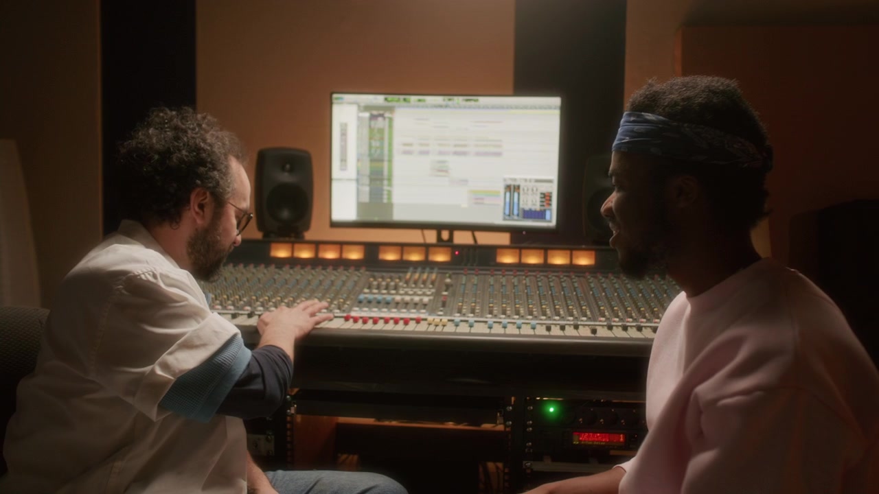 Musician and Sound Engineer Talking while Mastering Audio Tracks in Studio