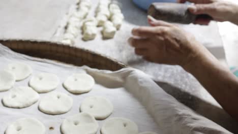 Cocinero-Chino-Enrollando-Masa-Cruda-En-Una-Ronda-Plana-Y-Perforando-Un-Agujero-En-Cada-Pieza-Usando-Un-Rodillo-De-Madera-Tradicional-Mientras-Se-Prepara-Para-Hacer-Pan-Plano-Chino-Con-Branquias-En-Horno-De-Arcilla-O-&quot;huping&quot;