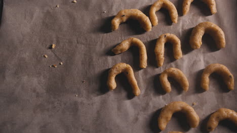 A-female-child-puts-freshly-made-cookie-dough-on-baking-paper-in-a-baking-tray-,-close-up-overhead-shot