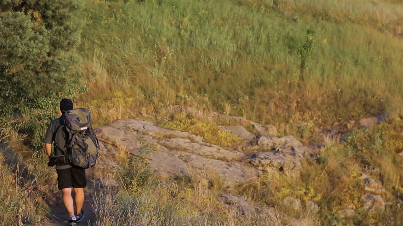 Hiker Going On A Stone. Adult hiker going along on a green hill