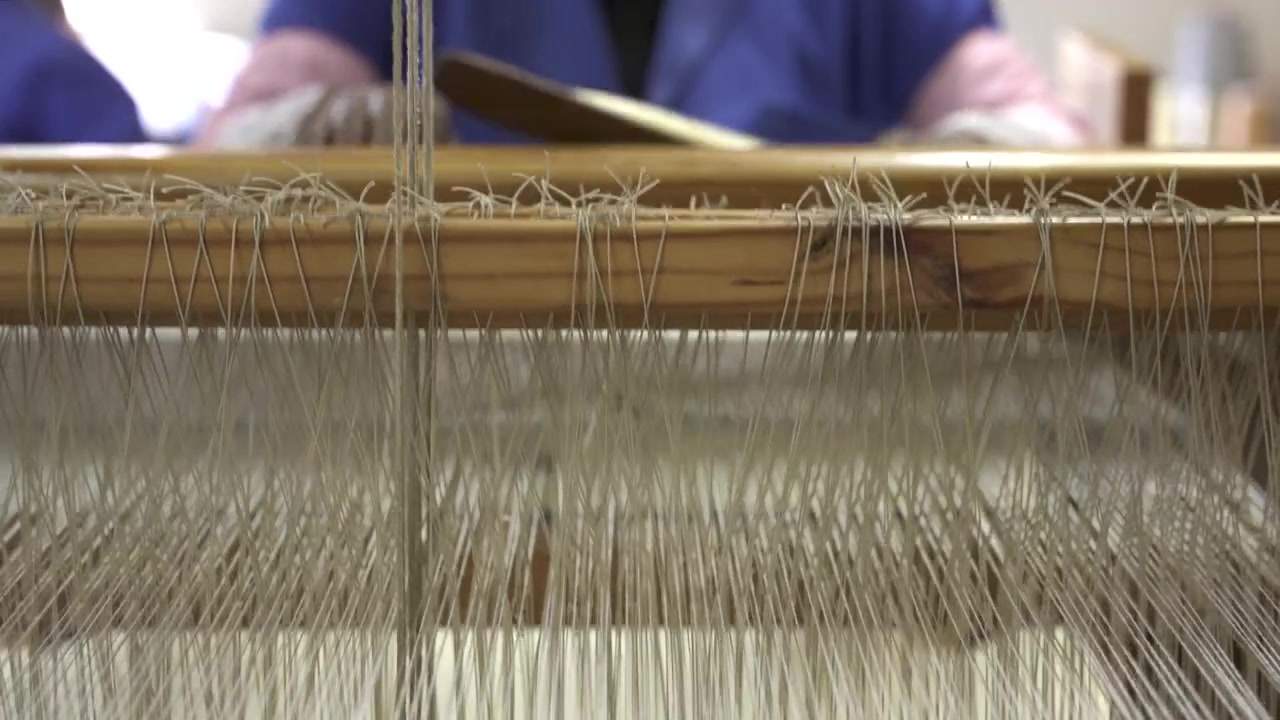 Close-up of threads moving on a traditional wooden loom, capturing the intricate weaving process. Ideal for educational content or craft-focused documentaries.