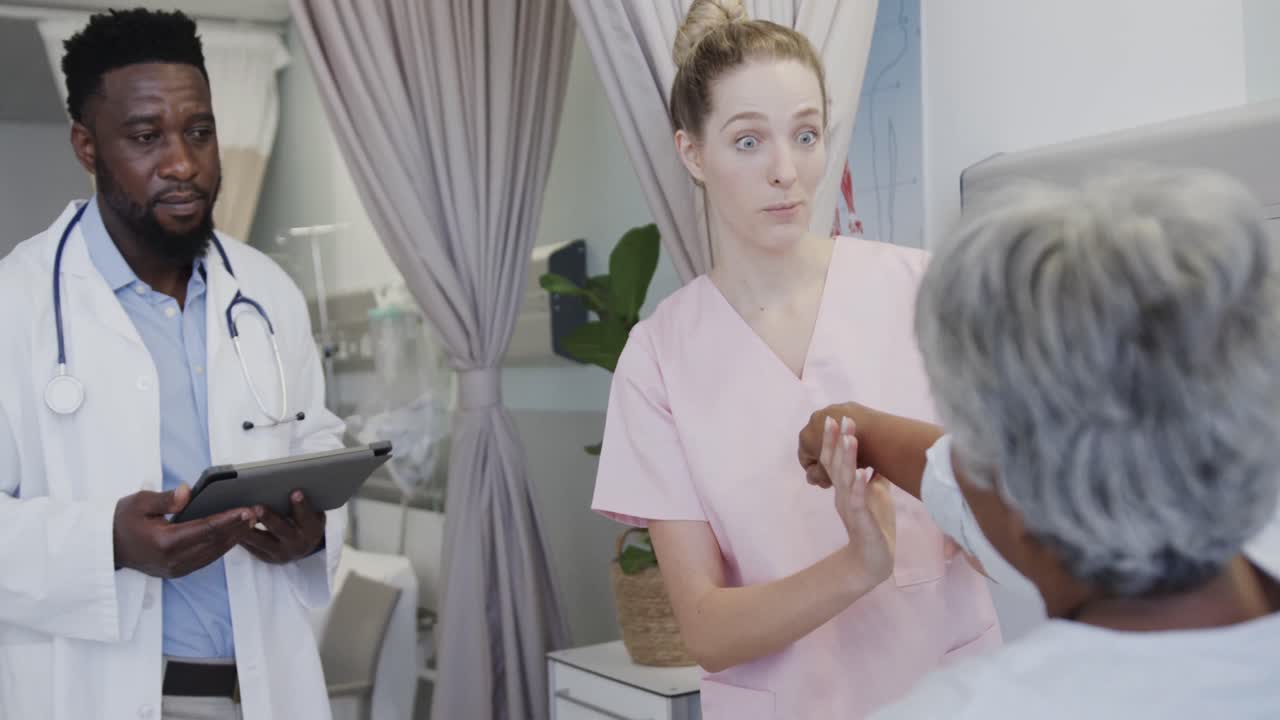 médico masculino diverso con tableta y fisioterapeuta femenina feliz tratando a una paciente femenina anciana, cámara lenta