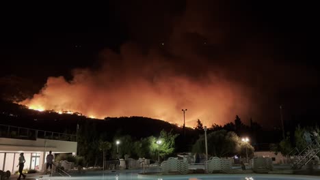 gran incendio forestal por la noche cerca de un hotel