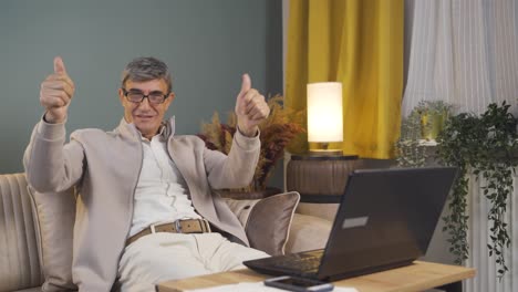 un anciano mirando la computadora portátil haciendo un gesto positivo.