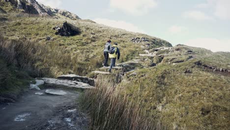 young couple getting up rocky path of a mountain