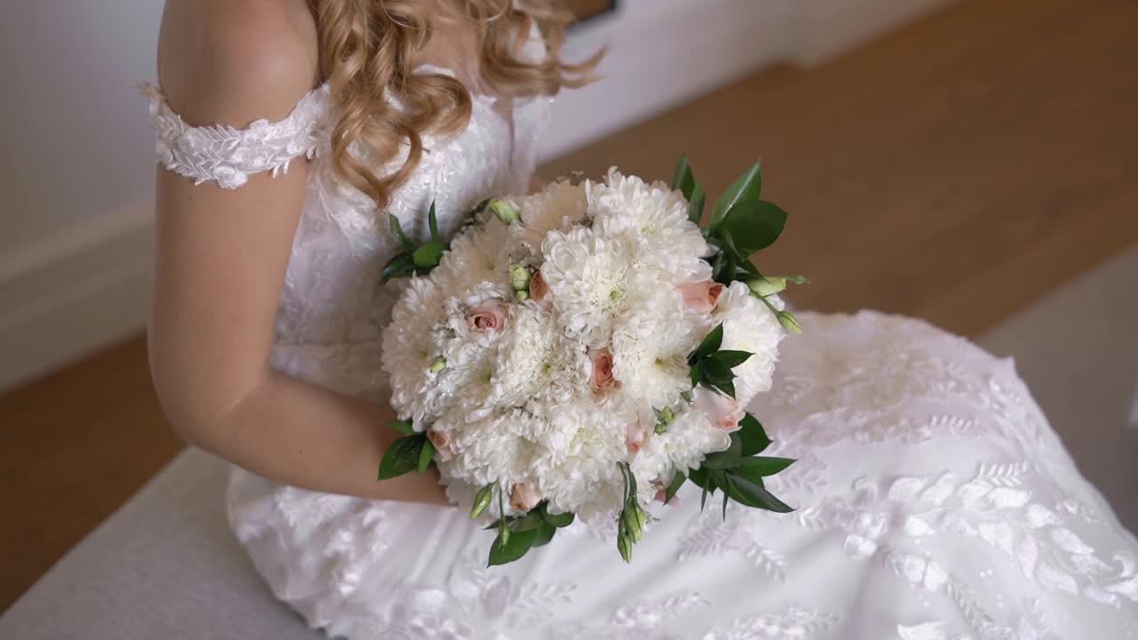 위에서 아래로 볼 때, 백인 신부가 아름다운 꽃봉오리를 들고 앉아 있습니다.