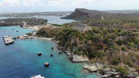 tugboat beach in curacao with clear waters and rugged coastline, aerial view