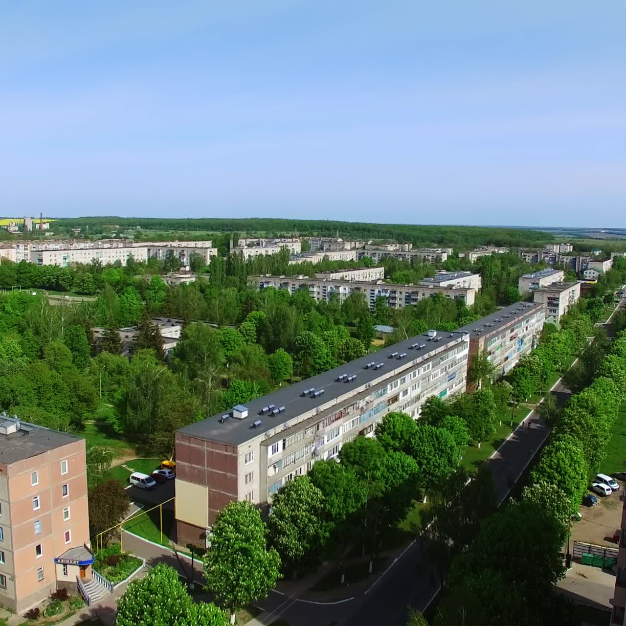 Green provincial city on hot sunny summer day. Quick drone flight over the square with fountain and residential area