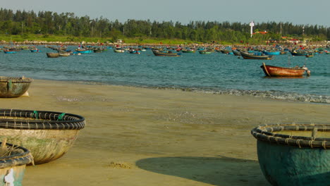 slow dolly past boats on the sand with boats floating in the ocean in da nang beach