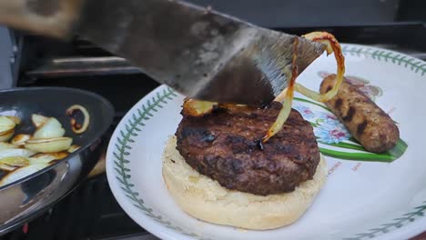 BBQ-Beef-Burger-and-Sausages-Being-Plated-with-Fried-Onions