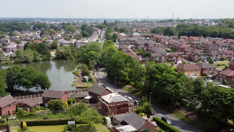 vista aérea se elevando acima de tijolo vermelho desenvolvimento de bairro britânico com lago enquanto os construtores trabalham na renovação do telhado