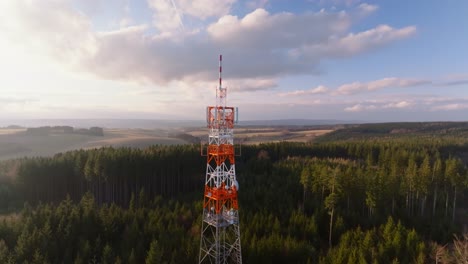 Parallax-Drohnenansicht-Eines-Turms,-Der-Nachmittags-Hoch-Zwischen-Einem-Wald-Steht