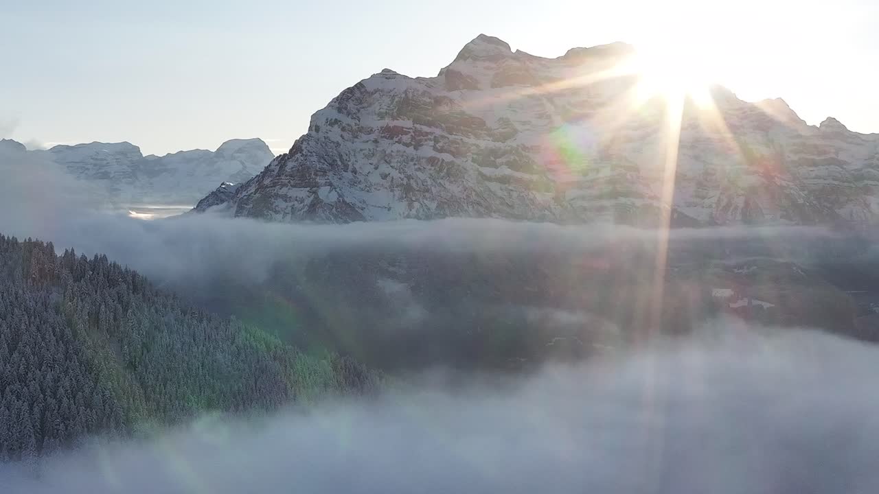 Sunrise illuminating Rautispitz and forested hills, Glarus Nord, Switzerland, above misty clouds