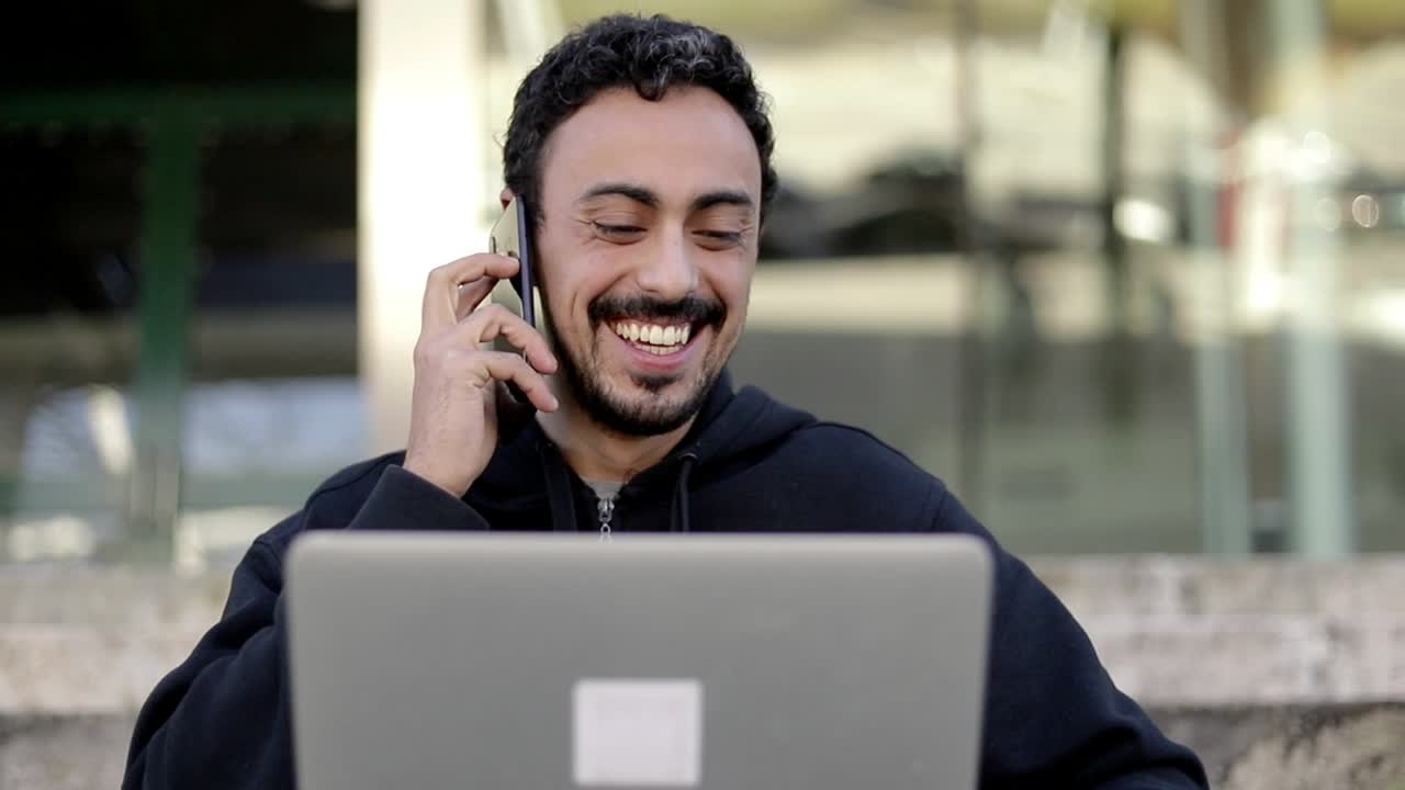 hombre de contenido usando portátil y teléfono inteligente