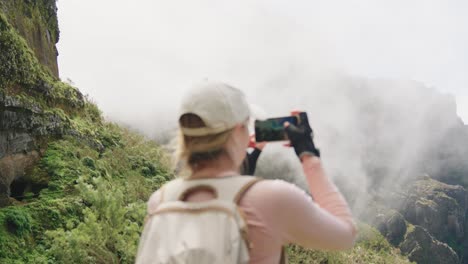 Travel-Girl-in-Cap-Taking-Photo-of-Fast-Moving-White-Clouds-in-Rocky-Mountains,-High-Mountains-Landscape