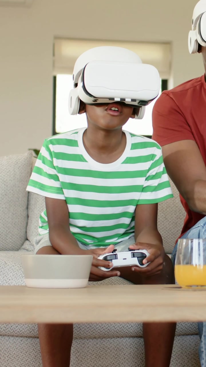 Bambino che reagisce alla VR, con maglietta a righe e visore bianco, che tiene un controller bianco sul divano.