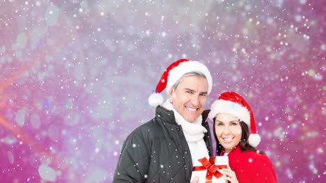 animación de una feliz pareja caucásica con sombreros de santa sobre la nieve que cae