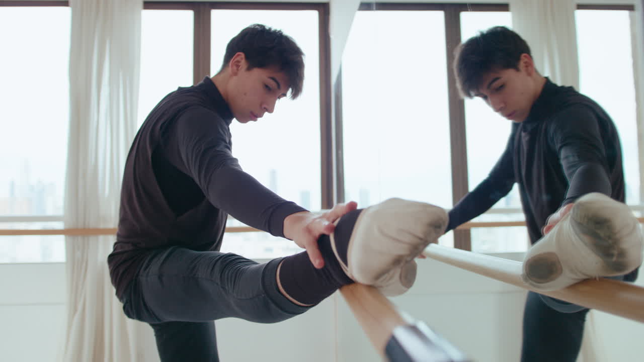 Young Male Ballet Dancer Doing Stretching Exercise at the Barre