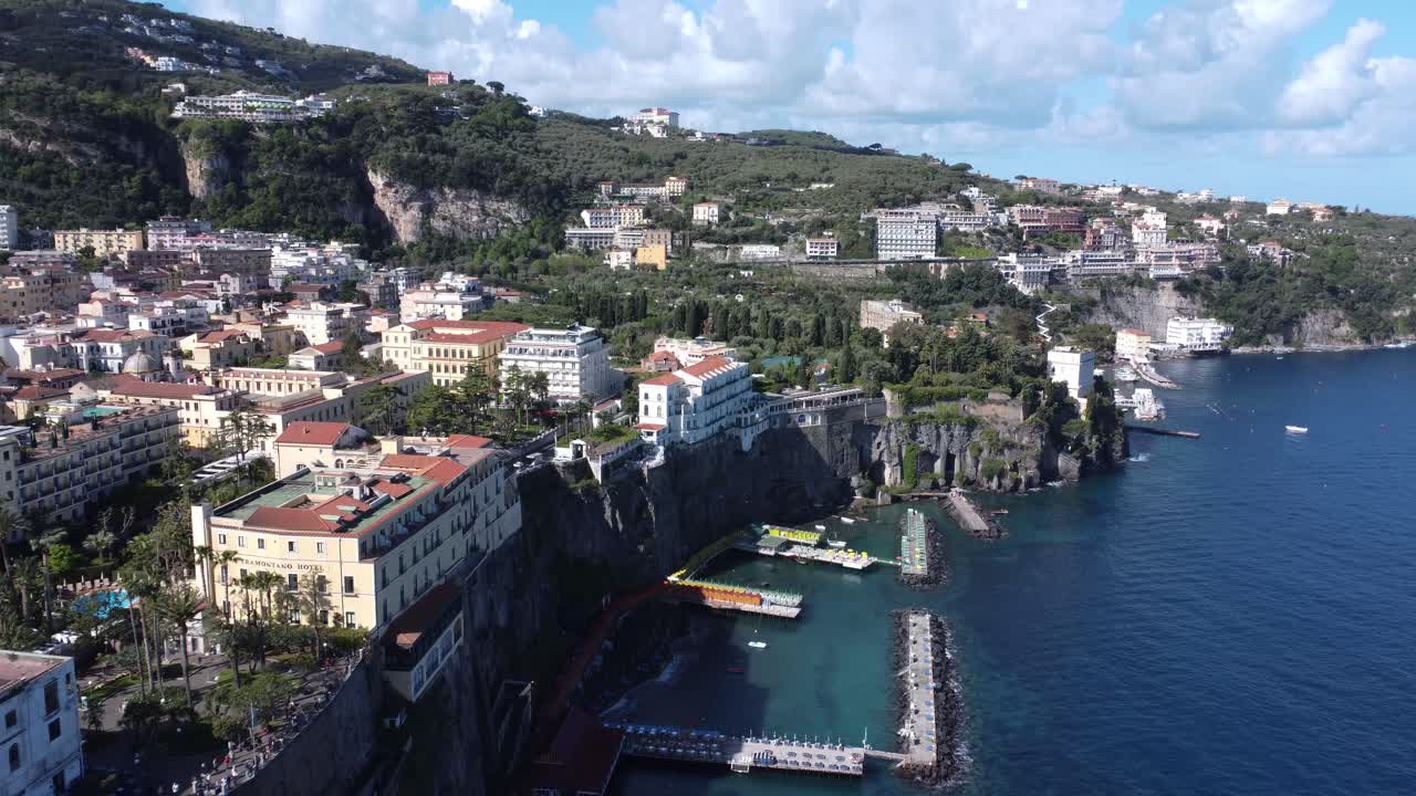 Waterfront buildings in Sorrento with seaside platforms and cliffs in drone video