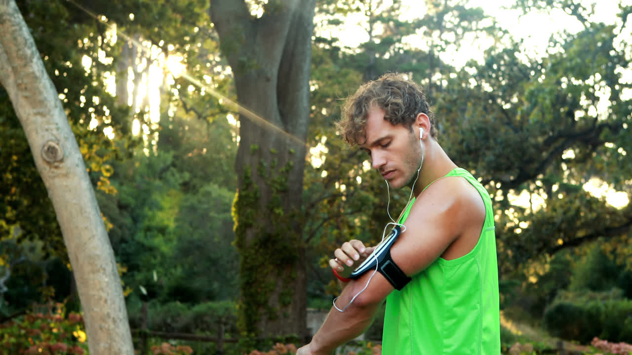 hombre ajustando los ajustes de música en la banda de brazo desde el teléfono inteligente
