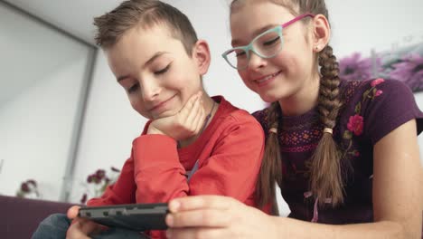 Happy-children-watching-movie-on-smart-phone-at-home.-Portrait-of-smiling-kids