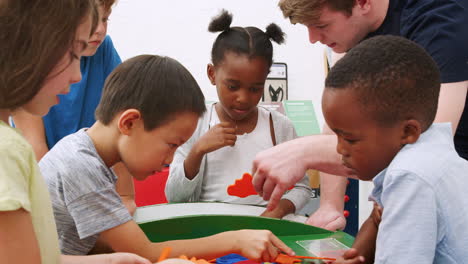 teacher doing a science puzzle with group of schoolchildren