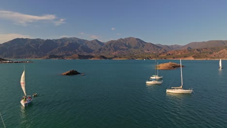 Backward-aerial-dolly-shot-revealing-anchored-sailboats-in-Mendoza,-Argentina