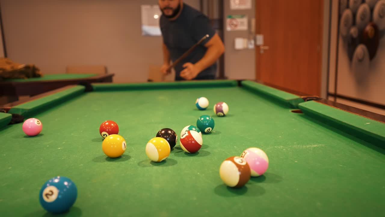 Casual player hitting starting position shot billiard balls triangle white cue ball seen in a distance sports game of billiards on green cloth