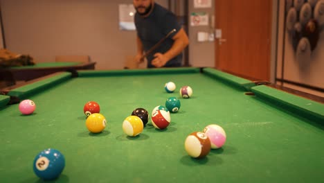 casual player hitting starting position shot billiard balls triangle white cue ball seen in a distance sports game of billiards on green cloth