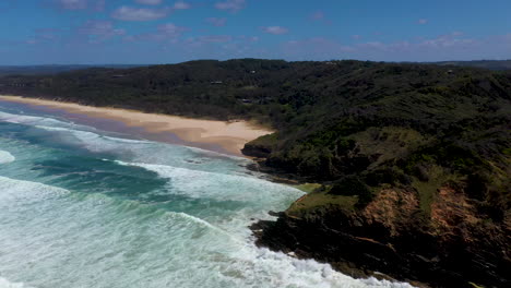 Wide-revealing-cinematic-drone-shot-of-ocean-and-island-at-Broken-Head-beach-in-Australia