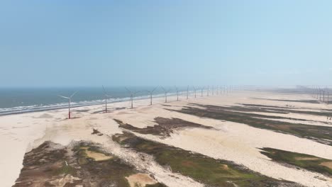 seaside wind turbines on beach by delta do parnaiba in brazil, aerial push-in