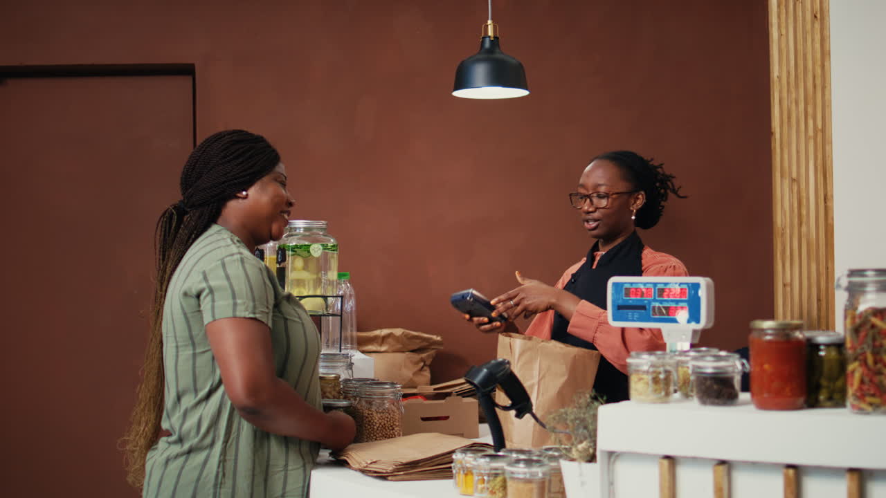 African american buyer paying with card at pos in eco store