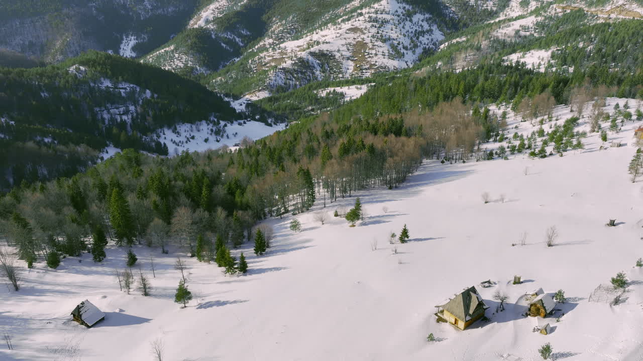 Aerial View of a Snowy Mountain Landscape with Winter Cabins and Forests