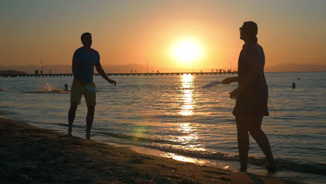 couple playing tennis on the beach at sunset