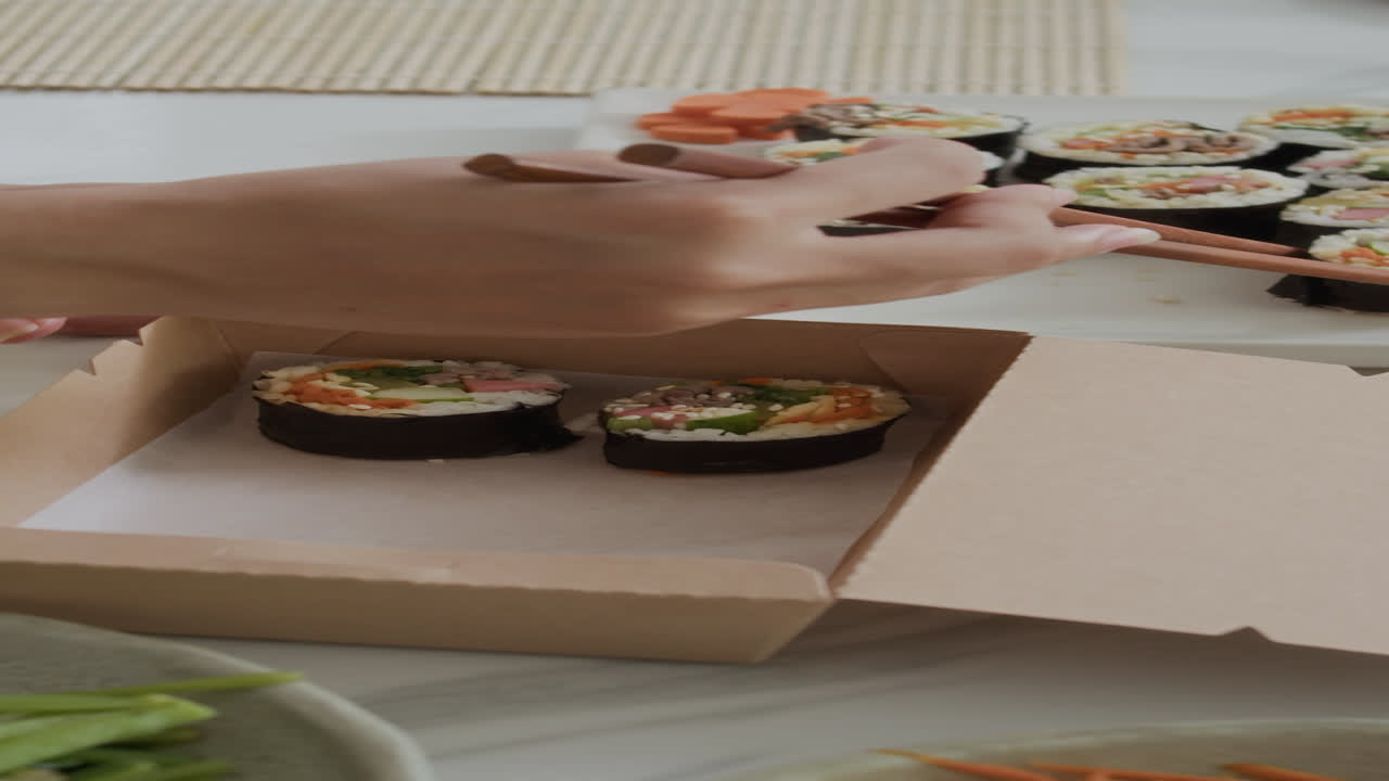 Anonymous Woman Using Chopsticks while Putting Self-made Kimbap in Carton Box