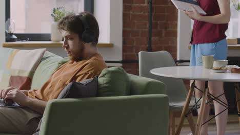 boy working on laptop computer while sitting on sofa in a shared flat