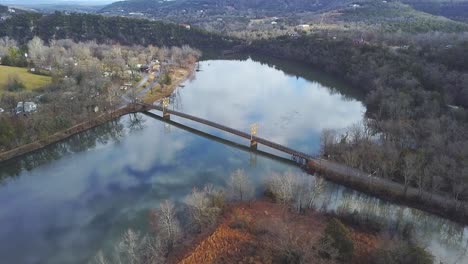 Parche-De-Luz-En-La-Orilla-Del-Río-Con-Un-Puente-Que-Cruza-El-Río