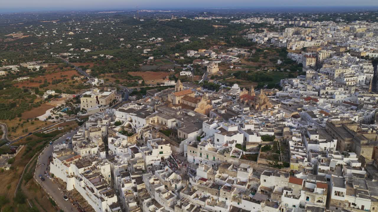 Ostuni, Puglia, Italia – Video aereo con drone durante l'ora d'oro, con ripresa orbitale della città vecchia imbiancata a calce e della cattedrale in cima alla collina, con uliveti e campagna all'orizzonte
