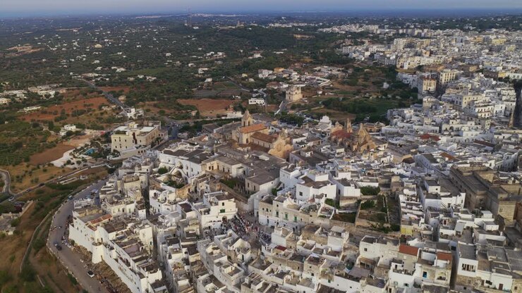 Ostuni, Puglia, Italia – Video aereo con drone durante l'ora d'oro, con ripresa orbitale della città vecchia imbiancata a calce e della cattedrale in cima alla collina, con uliveti e campagna all'orizzonte