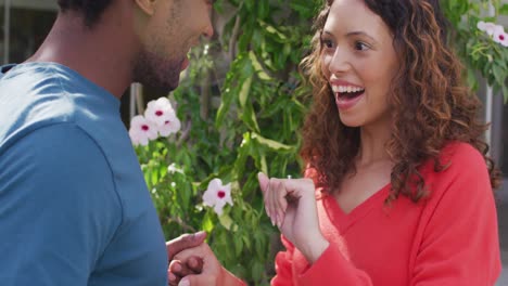 feliz mujer biracial mirando a la mano con anillo después de la propuesta