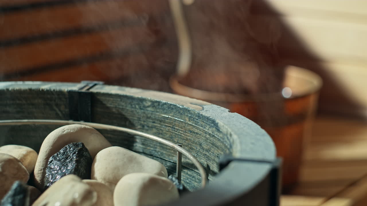 Throwing water on hot sauna stones in sauna stove, using a scoop or ladle and getting the water from a water bucket called a kip or pail