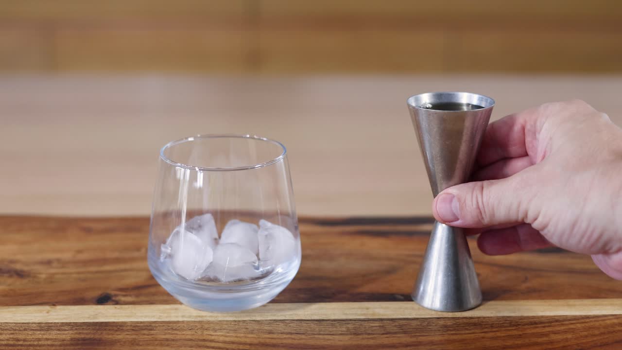 pasos secuenciales de verter whisky en un vaso con hielo