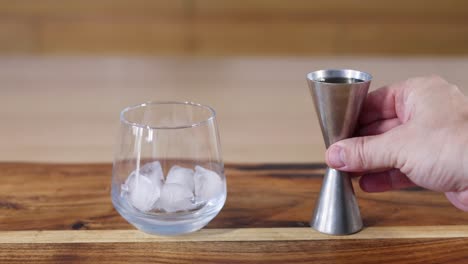 sequential steps of pouring whiskey into a glass with ice