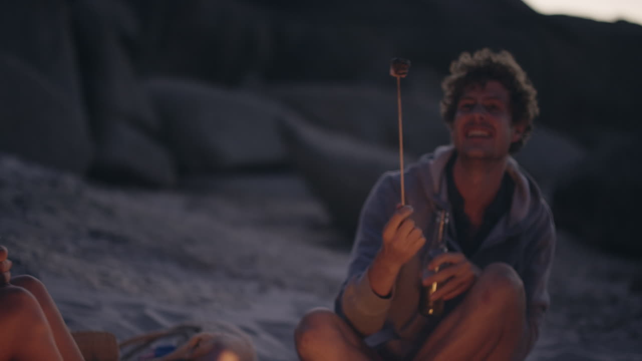 Beach Party at sunset with bonfire and roasting marshmellows with friends